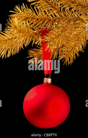 Red palla di Natale su un nastro su sfondo nero Foto Stock