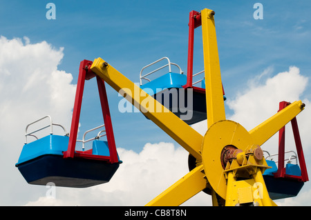 Coloratissima giostra nel parco a tema con estate blu cielo nuvoloso in background Foto Stock