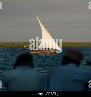 Dhow a vela nel canale, due alti uomini chiacchierando in primo piano, Lamu, Kenya Foto Stock