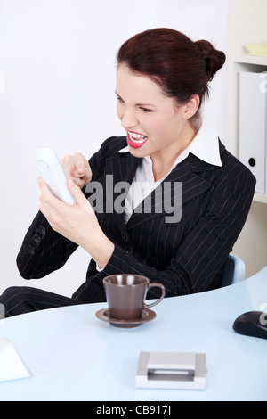 Ritratto di una giovane e bella donna d'affari essendo pieni di rabbia e follemente di comporre un numero di telefono durante la sua rottura. Foto Stock