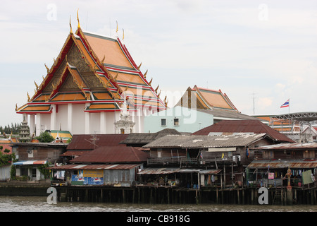 Tempio edificio accanto baracche sul Fiume Chao Phraya a Bangkok Foto Stock