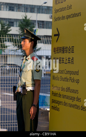 La guardia di sicurezza in uniforme sorge accanto al segno scritto in cinese, inglese e francese presso i Giochi Paralimpici a Pechino in Cina Foto Stock