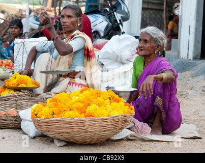 Le donne indiane che vendono fiori per festeggiamenti religiosi ghirlande al mercato in India Foto Stock