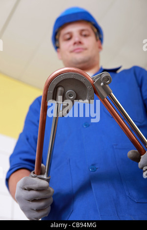 Tradesman con un attrezzo per flettere un utensile di rame Foto Stock