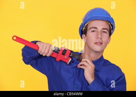 Ritratto di giovane plumber holding chiave regolabile contro sfondo giallo Foto Stock