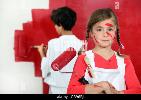 Bambini pittura un muro rosso Foto Stock