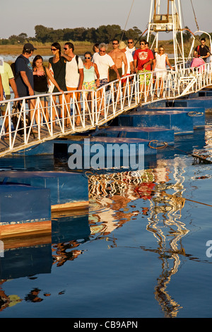 I vacanzieri di ritorno in serata sul ponte galleggiante da spiaggia Barril su Ilha de Tavira. Pedras d'el Rei. Algarve, Portogallo. Foto Stock