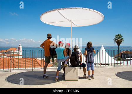 Famiglia affacciato sul quartiere di Alfama e il fiume Tago. Miradouro de Santa Luzia, Lisbona, Portogallo Foto Stock