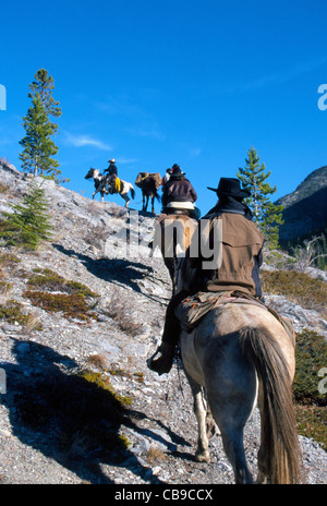 Equitazione su un viaggio di vacanza per arrampicarsi su un sentiero di montagna durante la loro avventura nel Parco Nazionale di Banff nelle Montagne Rocciose Canadesi in Alberta, Canada. Foto Stock