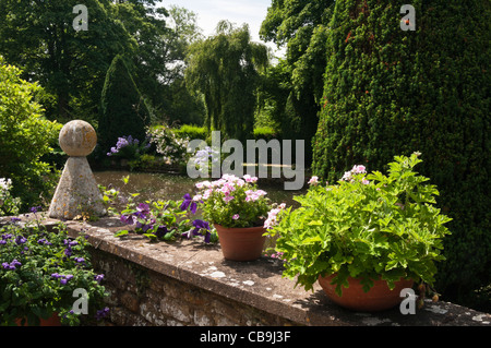 Terrazza giardino che si affaccia sul laghetto ornamentale a Coton Manor nel Northamptonshire, Inghilterra Foto Stock