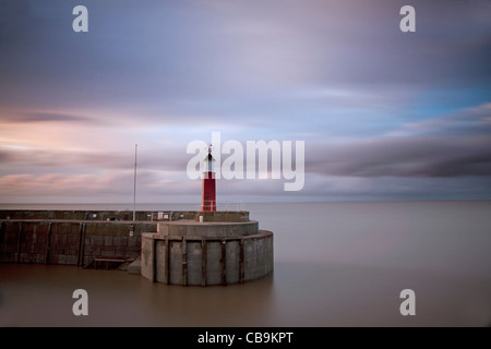 Watchet Harbour e il faro con morbidamente sfumata del cielo della sera. Foto Stock