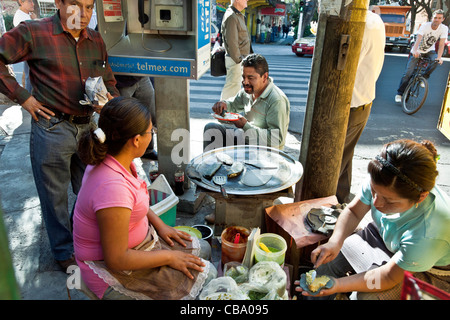 Due donne preparano blue corn tacos circondato da clienti soddisfatti mangiando sulla strada trafficata angolo quartiere Roma Città Del Messico Foto Stock