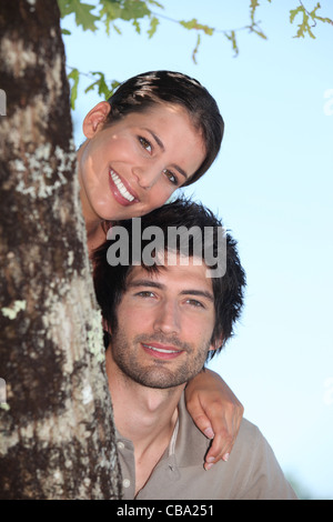 Paio di nascondersi dietro tree Foto Stock
