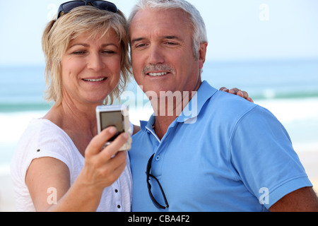 Coppia matura di scattare una foto di loro stessi in riva al mare Foto Stock