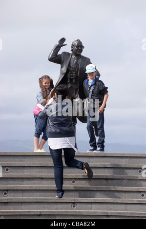 Una famiglia di prendere una fotografia presso la statua del comico Eric Morecambe sul lungomare, Morecambe, Lancashire, Inghilterra Foto Stock