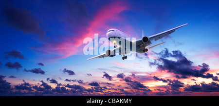 Gli aeromobili jet crociera in un Cielo di tramonto. Scatto panoramico. Foto Stock