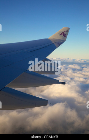 Vista attraverso il getto di passeggero finestra del Qatar aereo di linea ala, nuvole e cielo Foto Stock
