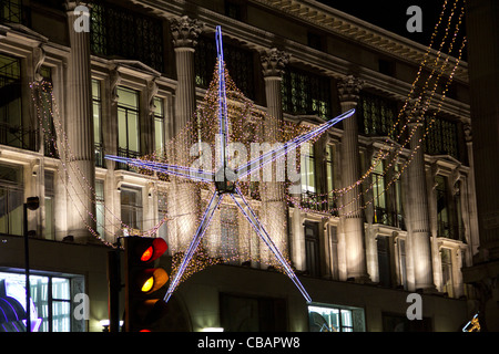 Oxford Street 2011 decorazioni di Natale, big blu luminoso e golden star nella parte anteriore di una fioca edificio e semafori. Foto Stock