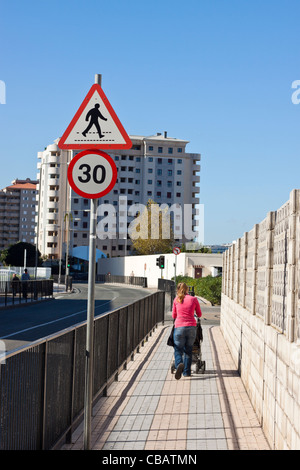 Donna con bambino trasporto camminando sulla strada di Gibilterra. Foto Stock