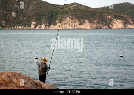 L'uomo la pesca sulle rocce da Tung Spiaggia Wan, Cheung Chau, Hong Kong outlying island Cina SAR Foto Stock