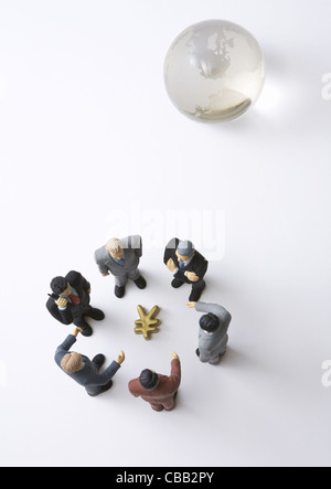 Gli imprenditori in miniatura che circonda yen segno e globo di vetro Foto Stock
