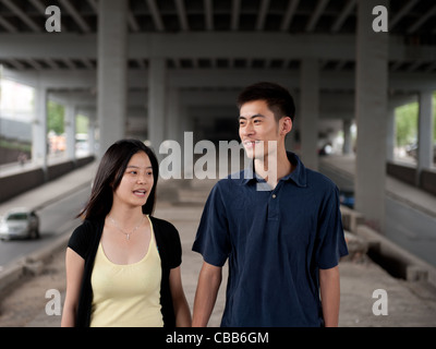 Coppia giovane sotto un ponte a piedi e in chat Foto Stock