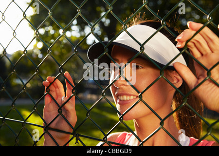 Donna del peering attraverso la catena collegamento recinto Foto Stock
