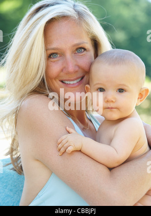 Sorridente madre holding baby all'aperto Foto Stock