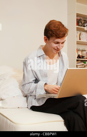 Uomo sorridente con notebook in salotto Foto Stock