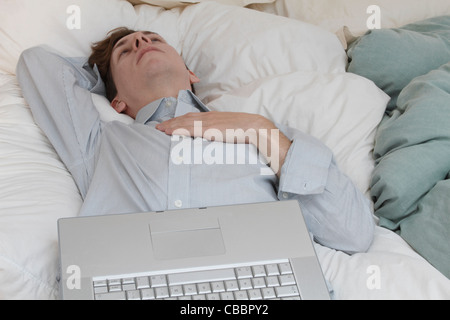 Uomo d affari con computer portatile la posa sul letto Foto Stock