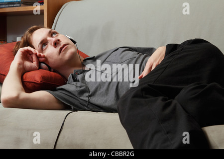 Uomo che ascolta le cuffie sul lettino Foto Stock