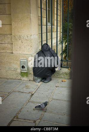 I senzatetto a forma di sacco il giardino di piante., dormendo seduta tranquillamente. Foto Stock