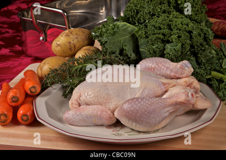 Materie di pollo intero su un tagliere con erbe e verdure Foto Stock