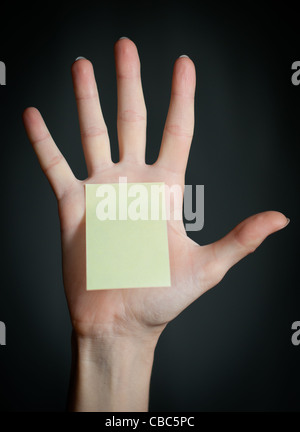 Femmina con mano sticky office nota su sfondo scuro . Nota è bianco e giallo Foto Stock