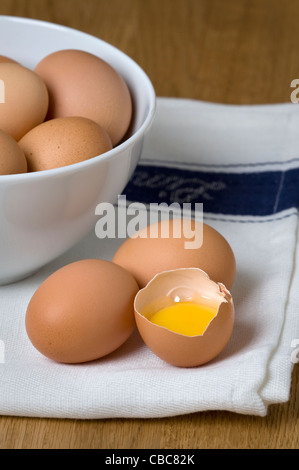 Brown uova di galline su un tè bianco asciugamano con un acciaio inossidabile Sbattere un uovo rotto e separata che mostra il bianco d'uovo e il tuorlo d'uovo Foto Stock