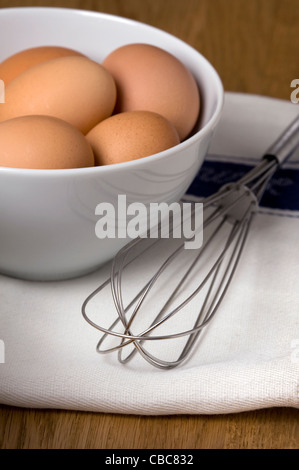Brown uova di galline su un tè bianco asciugamano con un acciaio inossidabile Sbattere un uovo rotto e separata che mostra il bianco d'uovo e il tuorlo d'uovo Foto Stock