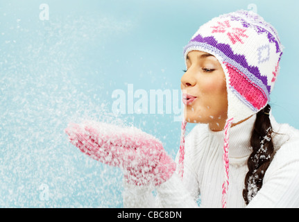 Immagine di Pretty Woman in rosa e guanti a maglia Cappello invernale lavori di soffiaggio della neve dai suoi palmi Foto Stock