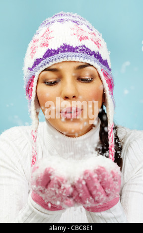 Immagine di Pretty Woman in rosa e guanti a maglia Cappello invernale lavori di soffiaggio della neve dai suoi palmi Foto Stock