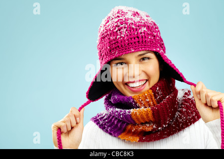 Foto di bella donna in maglia inverno cappello e sciarpa guardando la fotocamera con un sorriso Foto Stock