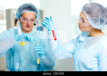 Fiducioso medico di studiare nuove sostanza in laboratorio con il suo collega sullo sfondo Foto Stock