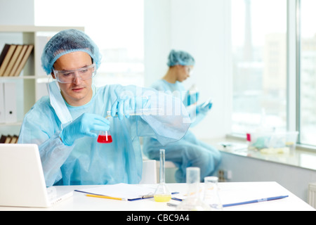 Fiducioso medico di studiare nuove sostanza in laboratorio con il suo collega sullo sfondo Foto Stock