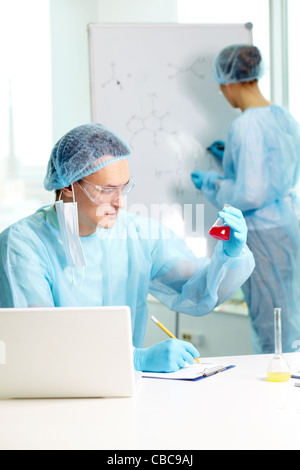 Fiducioso medico di studiare nuove sostanza in laboratorio con il suo collega sullo sfondo Foto Stock