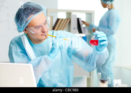 Fiducioso medico di studiare nuove sostanza in laboratorio con il suo collega sullo sfondo Foto Stock