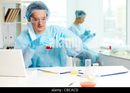 Fiducioso medico di studiare nuove sostanza in laboratorio con il suo collega sullo sfondo Foto Stock