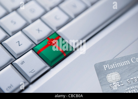 Dettaglio di una tastiera con una chiave avvolto come un regalo di Natale e una carta di credito presso l'angolo inferiore destro. Foto Stock