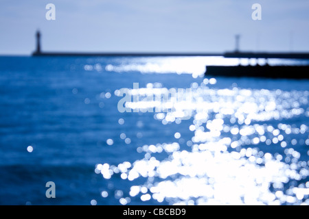 Mare blured faro con la luce del sole riflesso dalla superficie dell'acqua Foto Stock