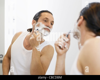 L'uomo la rasatura il suo volto nella stanza da bagno Foto Stock