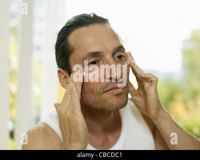 Uomo di applicare una crema idratante viso a Foto Stock