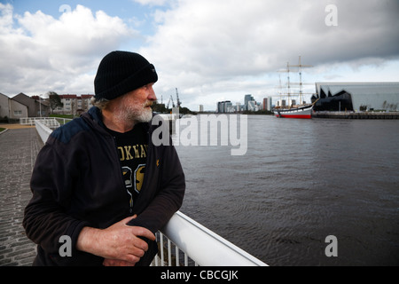 Disoccupato Adulto Uomo cerca su ringhiere da una passerella in Govan, attraverso il fiume Clyde al nuovo Riverside Museum Foto Stock