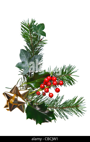 Foto di una decorazione di Natale realizzati con holly, bacche rosse, abete, edera e un nastro d'oro bow, isolata su uno sfondo bianco. Foto Stock